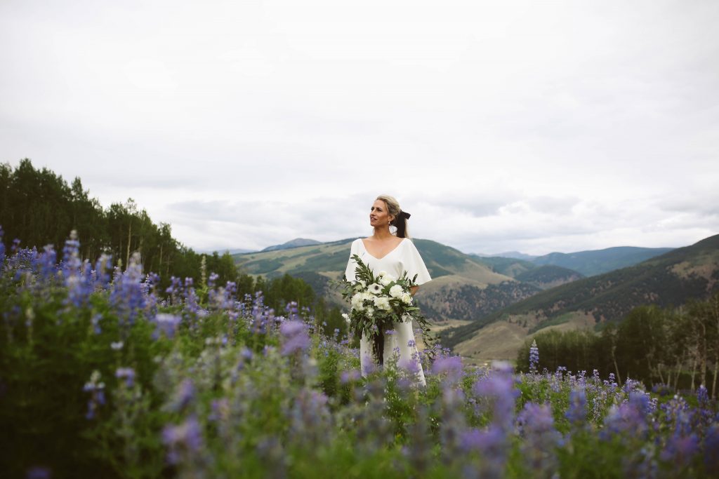 Bride standing in a field of wildflowers and lupine