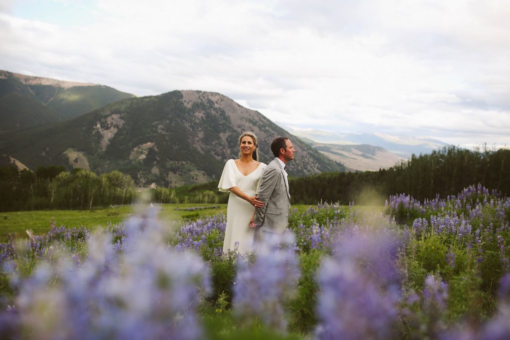 Bride and groom standing in a field of wildflowers lupine