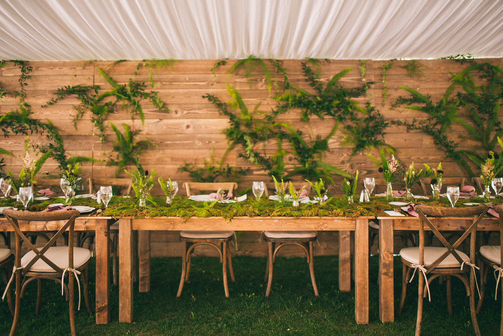 wedding head table with wood wall and greenery