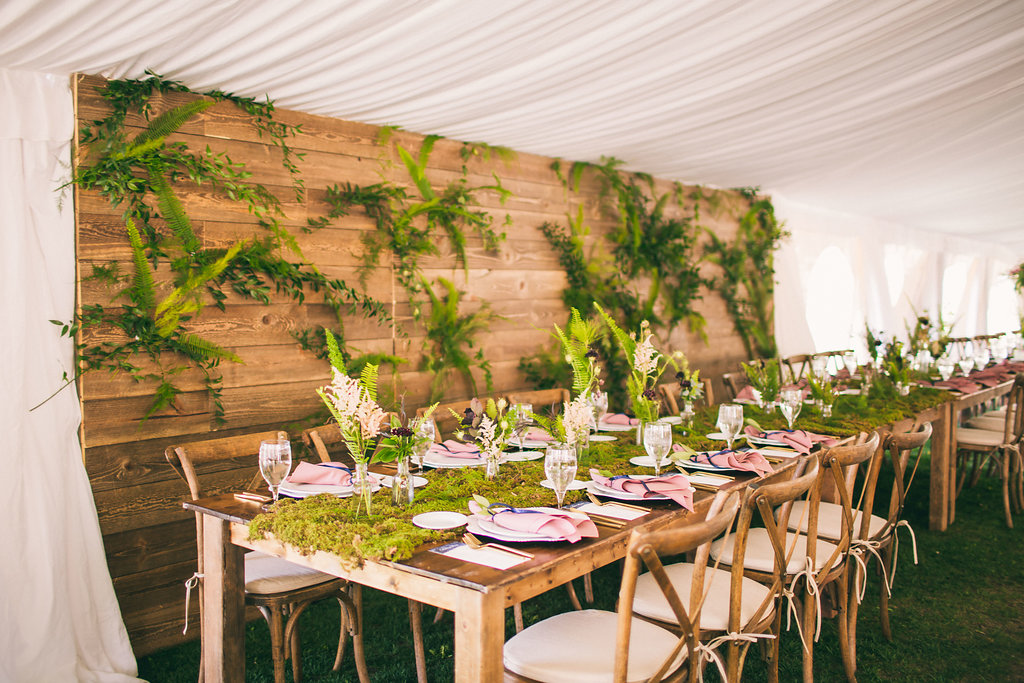 head table with wood wall cover in greenery and farm tables and cross back chairs