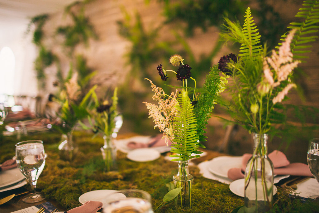 wedding dinner table with moss and small arrangements